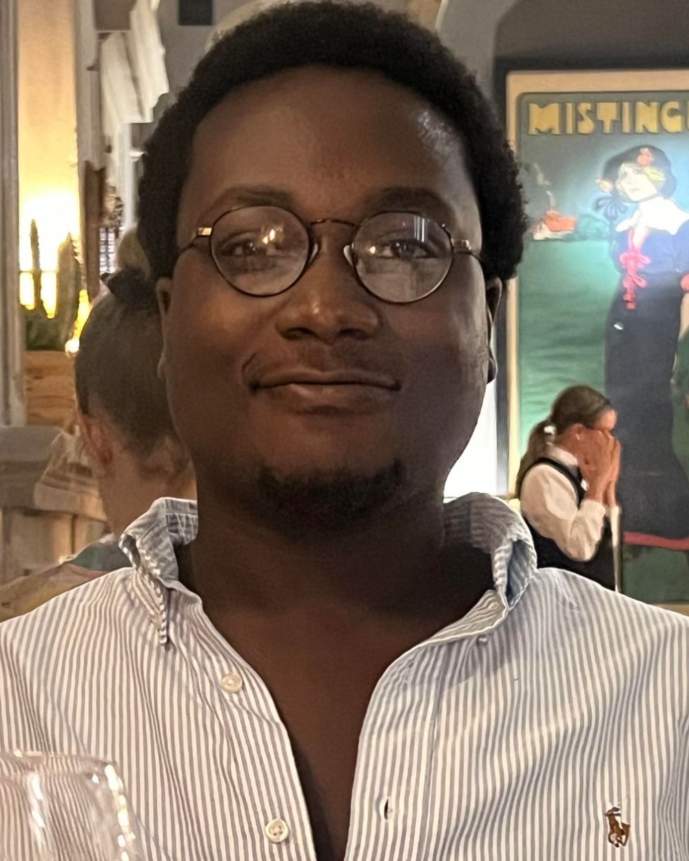 Kevin Brefo, smiling, in round glasses and a striped shirt.